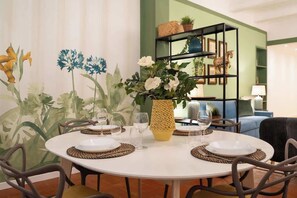 A dining area with a round table set for four, surrounded by chairs. There is a decorative vase with flowers on the table.