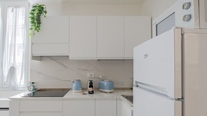 Une cuisine moderne avec des meubles blancs, un four encastré, un réfrigérateur et un évier.