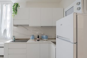 Une cuisine moderne avec des meubles blancs, un four encastré, un réfrigérateur et un évier.
