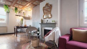 Un salon avec une cheminée, un coin repas avec des chaises, un canapé et une plante suspendue.