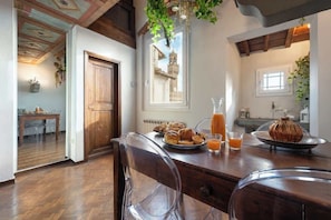 Un comedor con mesa de madera, sillas y productos para el desayuno.