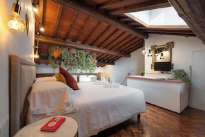 Una habitación de hotel con cama, escritorio, televisor y tragaluz.