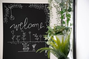 A blackboard with a 'welcome' sign surrounded by plant drawings and a hanging light bulb.