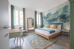 A bedroom with a bed, a desk, a chair, a mirror, and a large abstract painting on the wall.