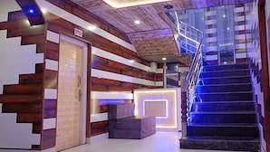 A modern hotel interior with a wooden wall design, a reception desk, and a staircase with blue lighting. - Hotel Pahalgam View (Anantnag)