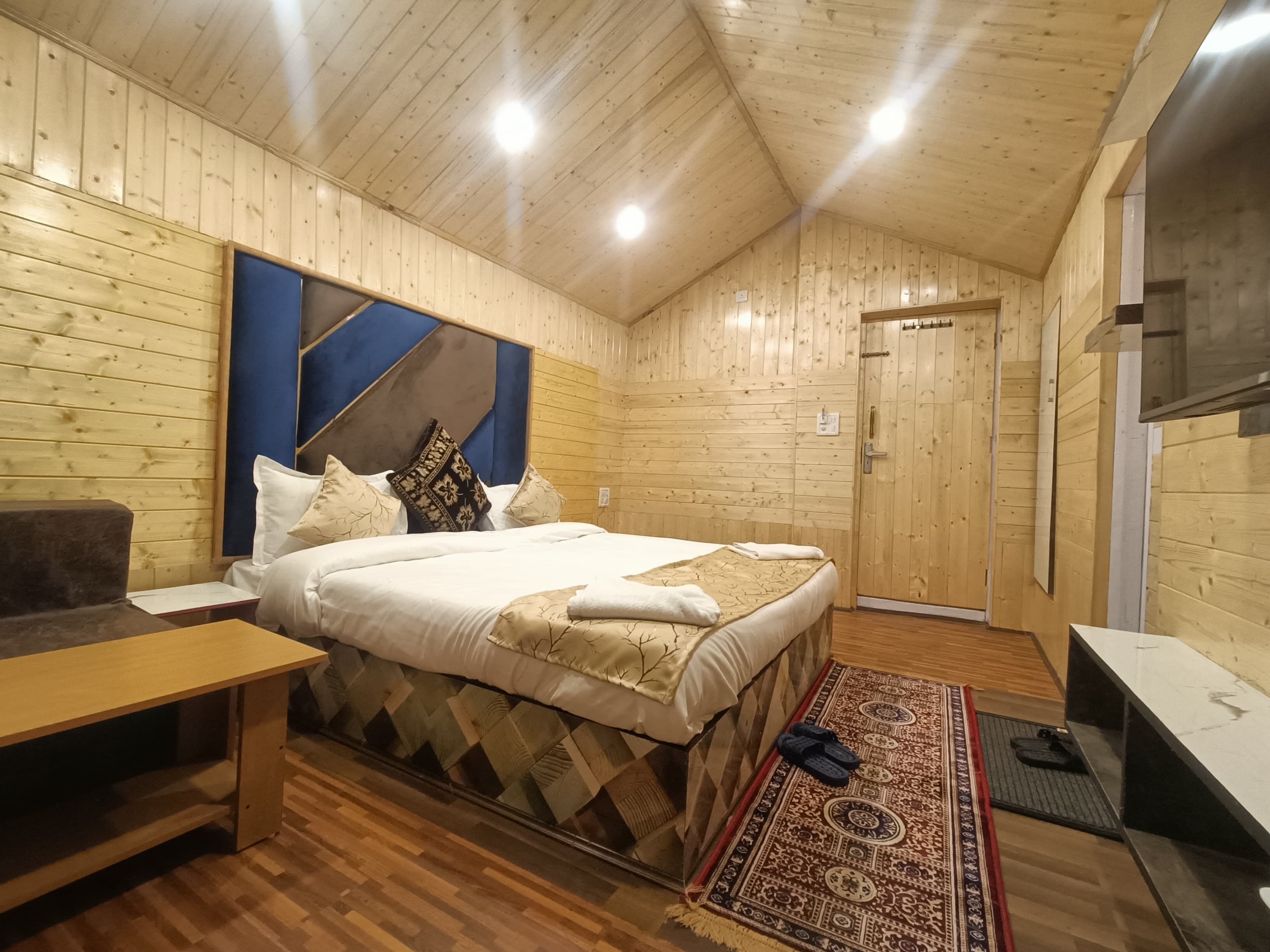 Una habitación con paneles de madera, una cama, un sofá, un escritorio y un televisor.
