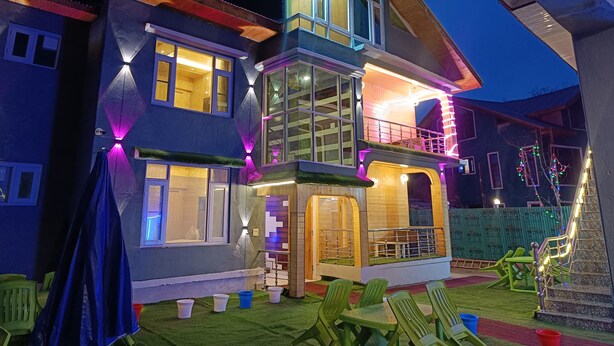 A multi-story house with a balcony and a covered outdoor seating area. - Hotel Pahalgam View (Anantnag)