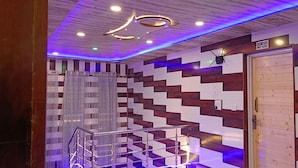 A modern interior with a wooden and white patterned wall, a staircase with metal railings, and a ceiling with recessed lighting and blue LED strips. - Hotel Pahalgam View (Anantnag)