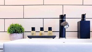 A bathroom with a white sink, black faucet, and three bottles of soap on a shelf.