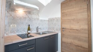 Una cocina con una puerta de madera, un lavabo y una botella de vino sobre la encimera.