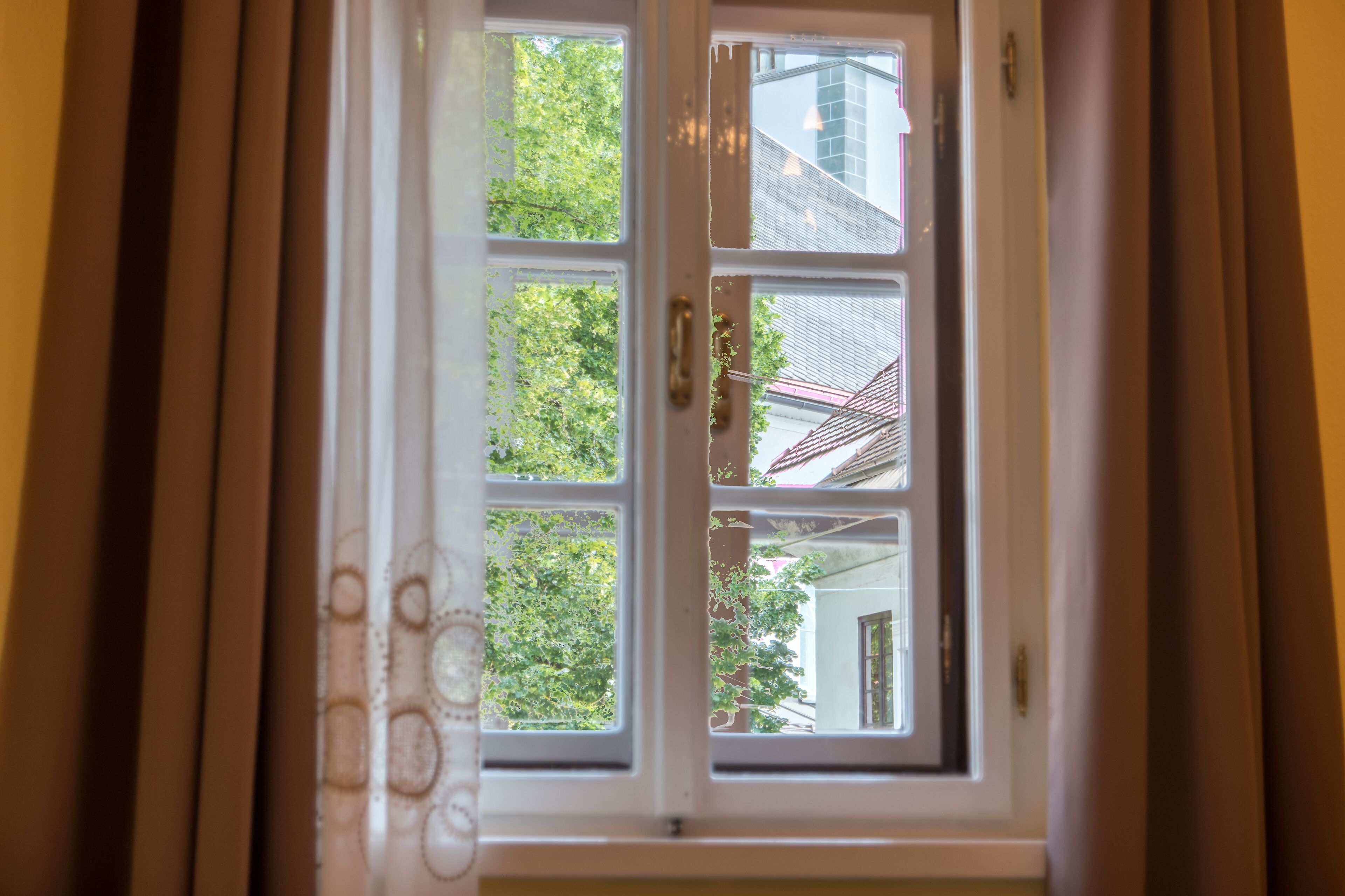 Ein Fenster mit Blick auf ein Gebäude und Bäume.