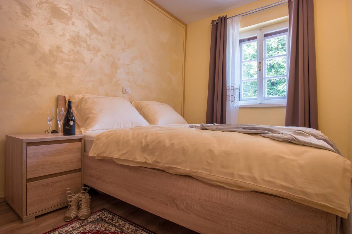 Un dormitorio con una cama de madera, una mesita de noche y una ventana con cortinas.