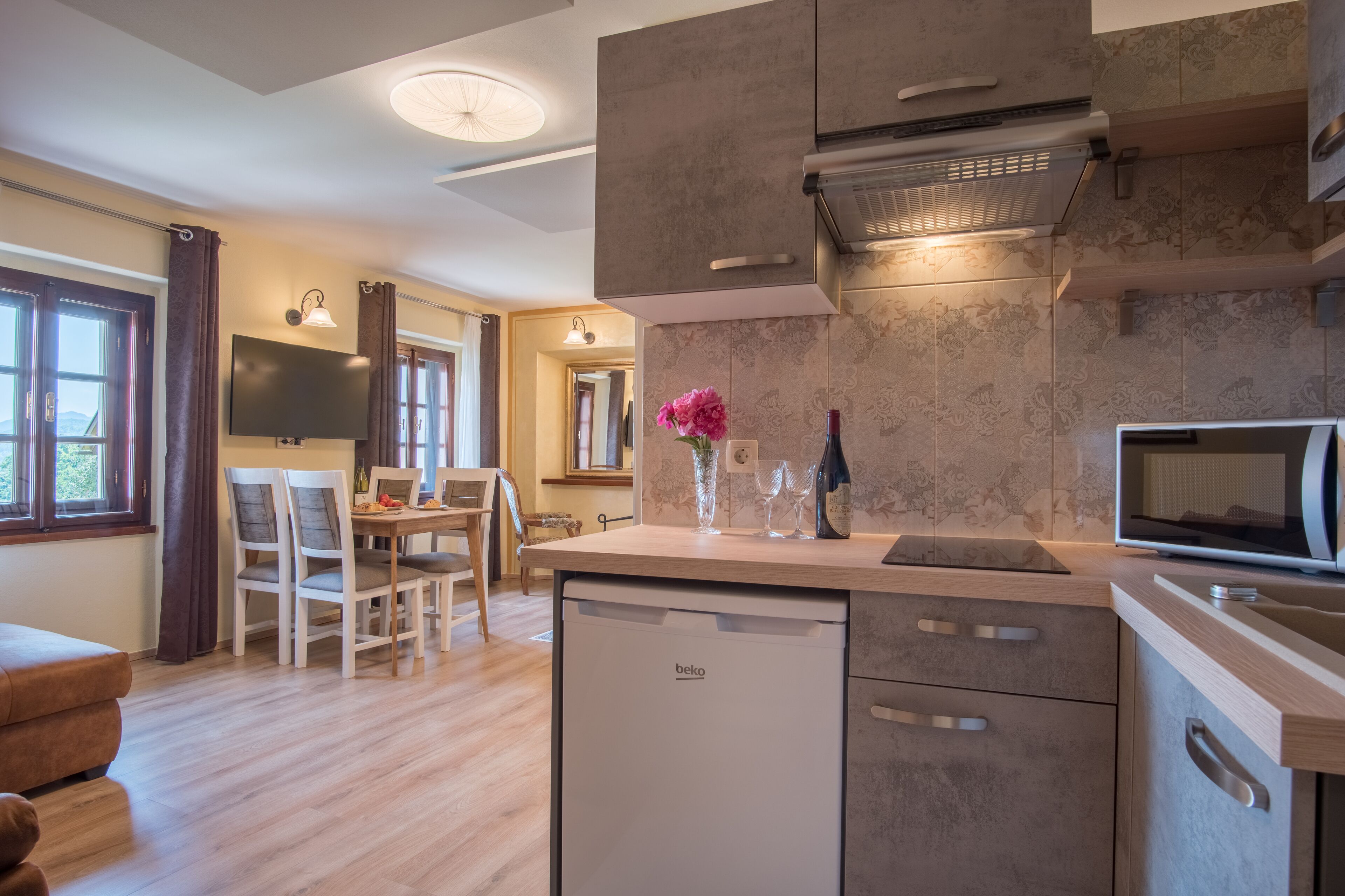 A modern kitchen with a dishwasher, microwave, and a dining area with chairs and a table.