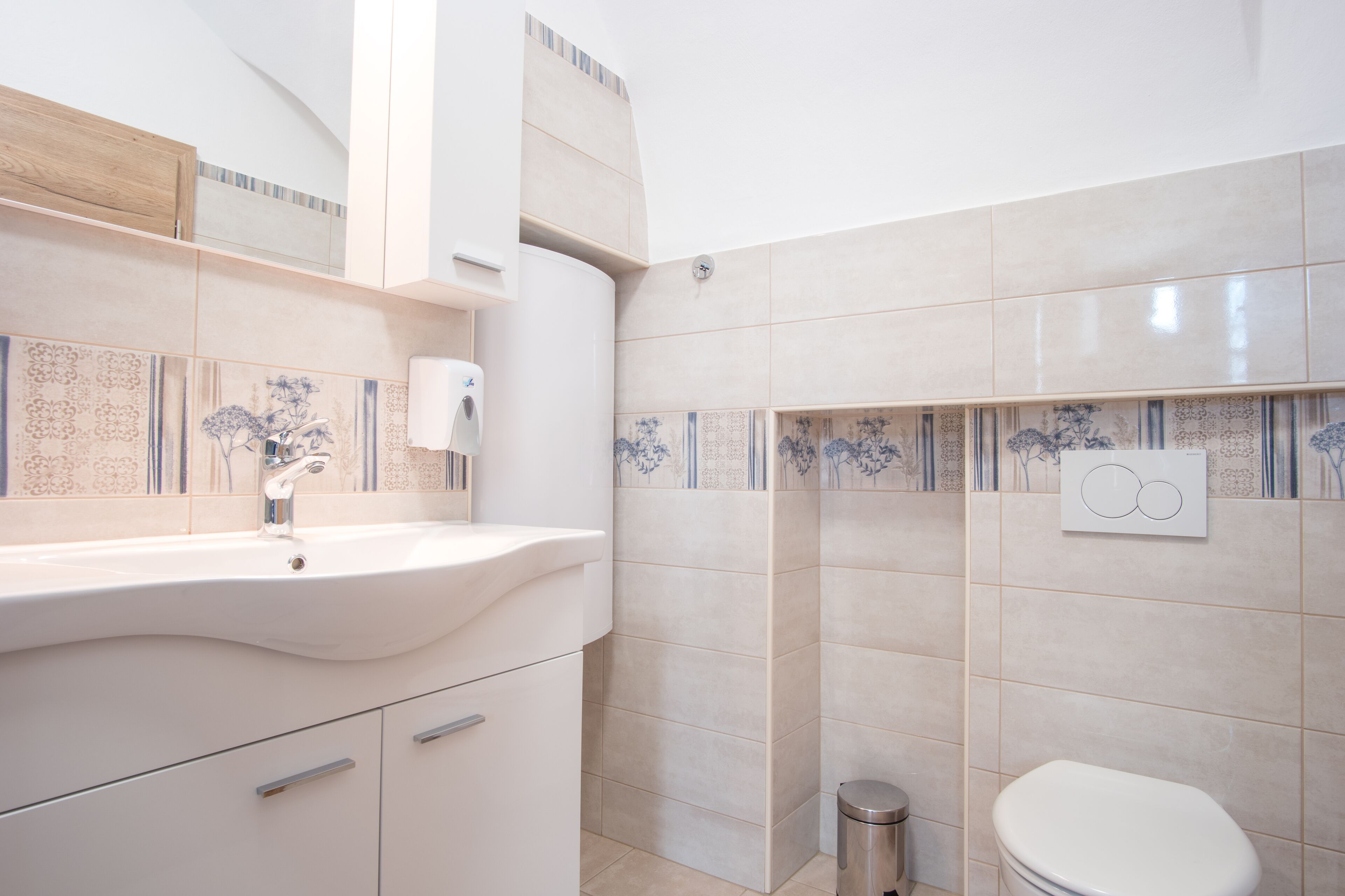 A modern bathroom with a white sink, vanity, and toilet.
