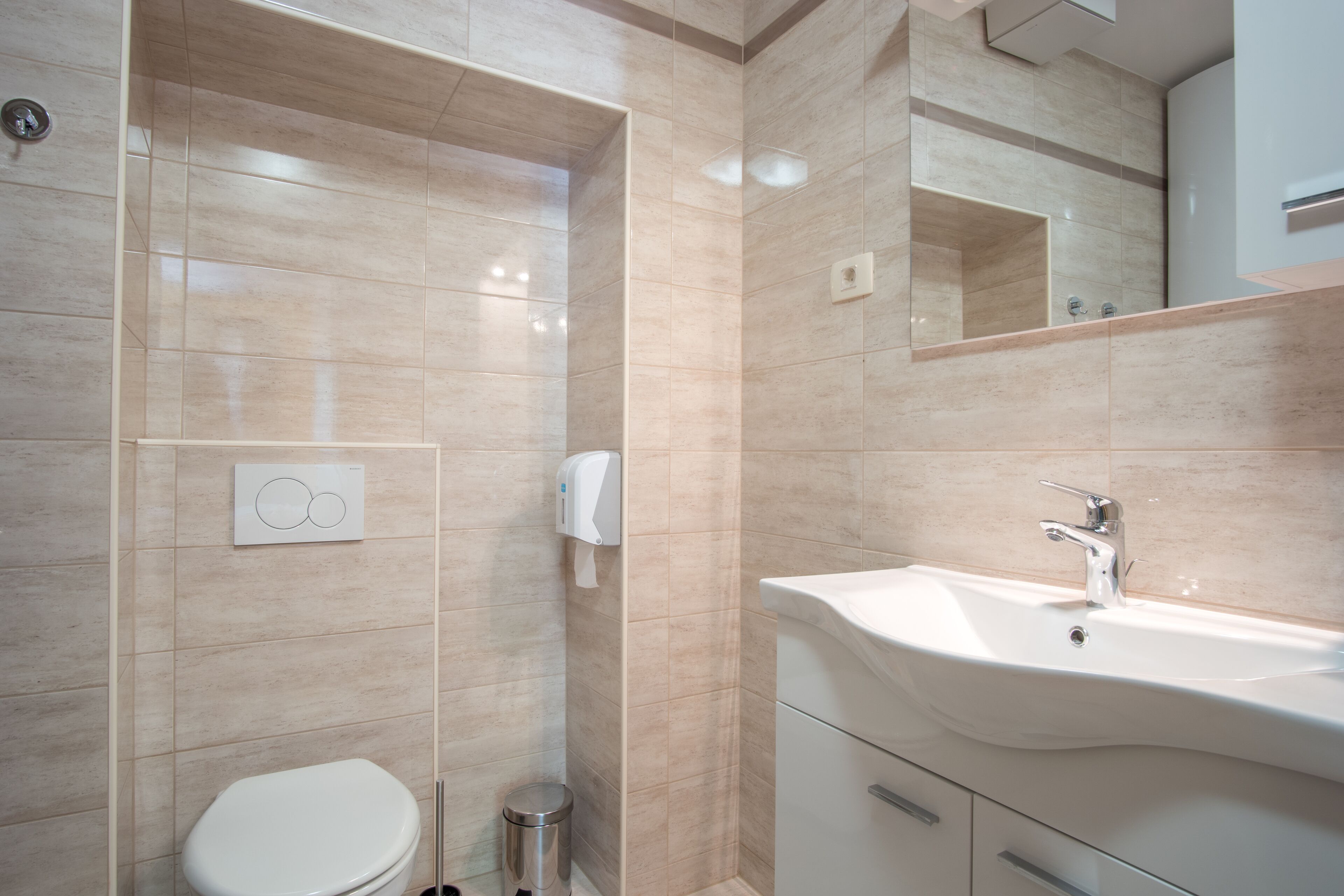Un baño moderno con inodoro, lavamanos y secador de manos.