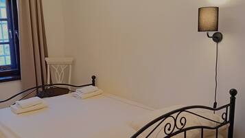 A neatly made bed with white linens, a black metal headboard, and a wall-mounted lamp.