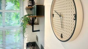 A modern kitchen with a large wall clock, built-in shelves with plants, and a kettle on the counter. - Cosy and Stylish Studio Apartment
 (Trowbridge)