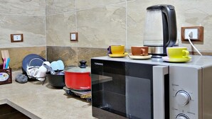 A kitchen with a microwave, toaster, and kettle on the counter. There are dishes and utensils in the sink. - City Center: Modern 2BR Flat-56 (Cairo Governorate)