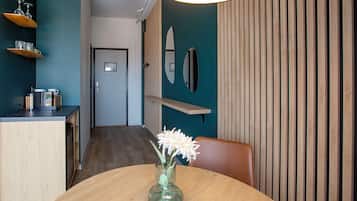 Ett modernt matområde med ett träbord, en vas med blommor och utsikt över en hall med en dörr och en surfbräda som hänger på väggen.