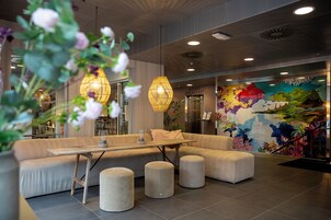 Un vestíbulo moderno con área de estar, una mesa de comedor y un mural en la pared.