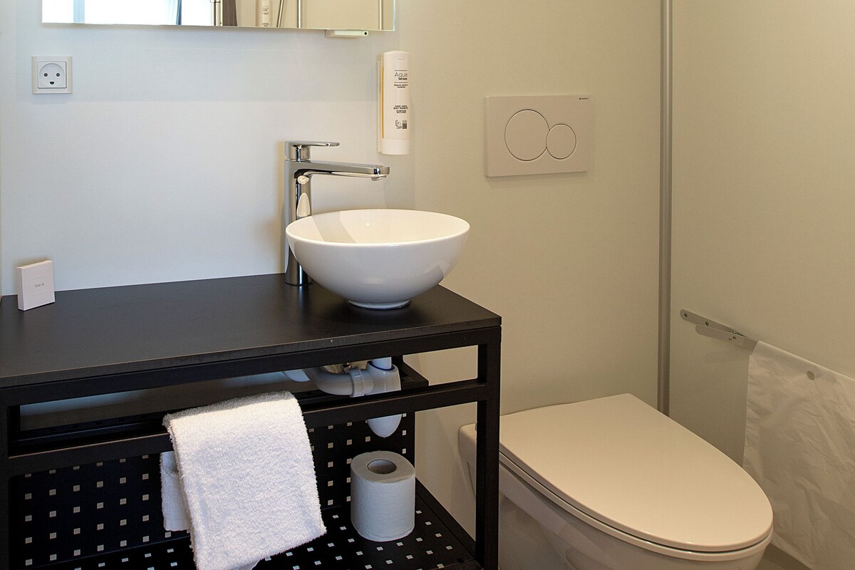 A modern bathroom with a white sink, black countertop, and a toilet.