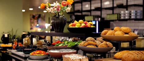 Un buffet proposant une variété de plats, notamment des fruits, des légumes et du pain.