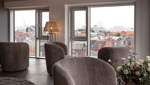 A modern living room with large windows, a lamp, and a potted plant. - CABINN Plus Esbjerg (Esbjerg)