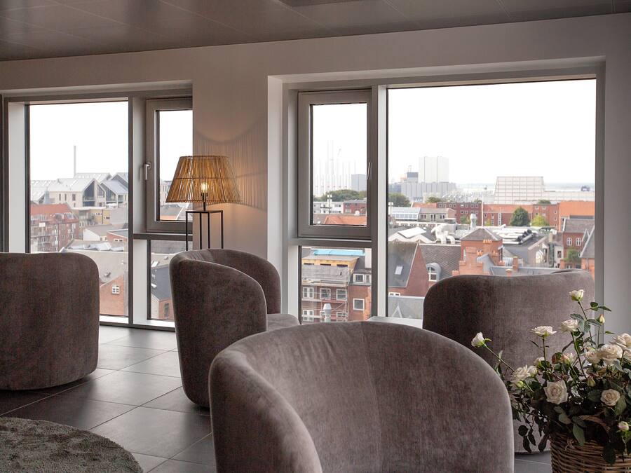 Una sala de estar moderna con ventanas amplias, una lámpara y una planta en maceta.