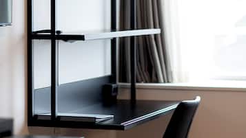 Un espacio de trabajo moderno con un escritorio negro, una silla y un televisor montado en la pared.
