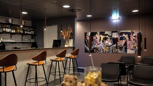 A bar area with stools, a counter with bottles, and a painting on the wall. - CABINN Plus Esbjerg (Esbjerg)