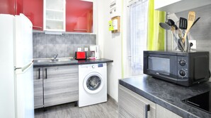 Una cocina compacta equipada con lavadora, microondas y cafetera.