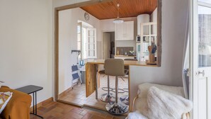 Une cuisine avec des meubles de rangement en bois, un tabouret de bar et une table à manger.