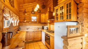 Cocina de cabaña de madera con estufa, pileta y alacenas.