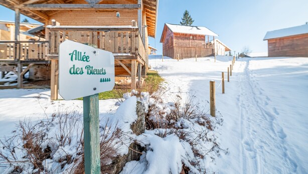 A wooden cabin with a sign reading "Allee des Blauen".
