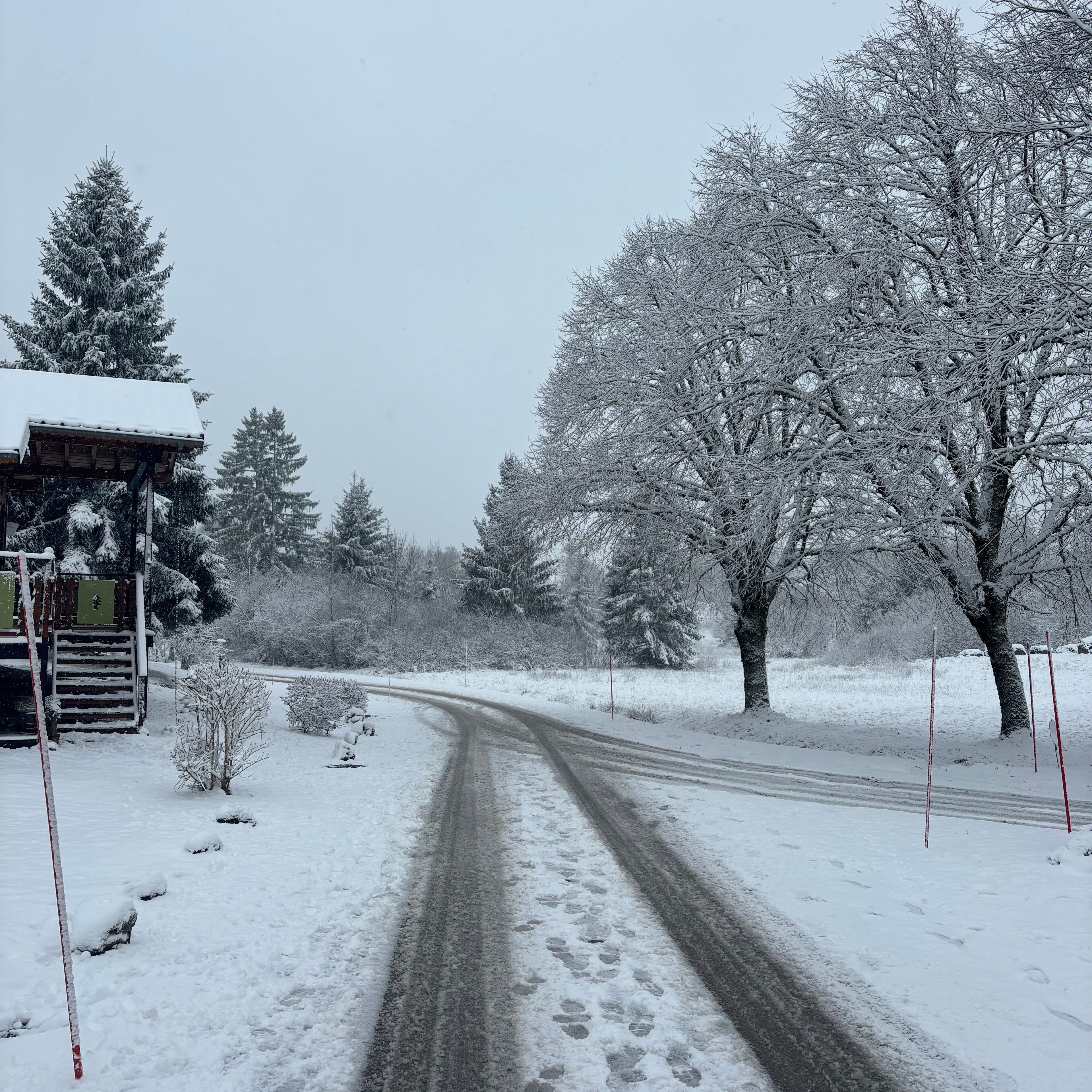 A snow-covered rural road with a building on the left.