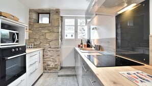 A modern kitchen with a stone accent wall, built-in appliances, and a wooden countertop.