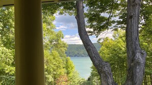 A view from a porch with a railing, overlooking a lake surrounded by trees.