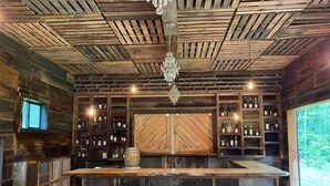A rustic bar area with wooden shelves and a central bar counter. - ParkPlaceKeuka FingerLakes: Fab Lake Views,HikingTrails w/TeaHouse on Waterfall! (Branchport)