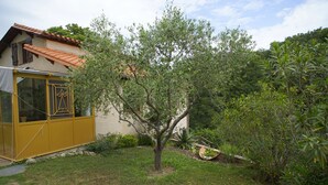 A house with a yellow exterior, a small garden with a tree, and a view of a hill. - Studio Avec Véranda Dans Vallée Calme à Reynès (Reynes)
