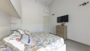 Ein Schlafzimmer mit einem Bett, einem Schminktisch, einem Fernseher an der Wand und einer Tür.