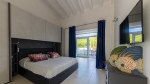 Ein modernes Schlafzimmer mit einem großen Bett, einem Flachbildfernseher und einem Balkon mit blauen Vorhängen.