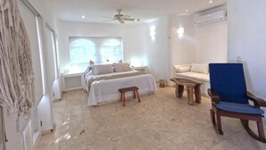 A spacious room with a bed, a blue chair, a small table, and a ceiling fan. - Christmas Deal!Oceanview private pool villa, steps from the beach. 24hs security (Playa del Carmen)