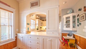 Une cuisine avec des meubles blancs, un îlot central et un coin repas agrémenté de chaises colorées.