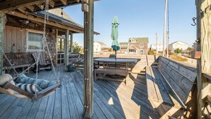 Une terrasse en bois avec une chaise suspendue, une table et un parasol.