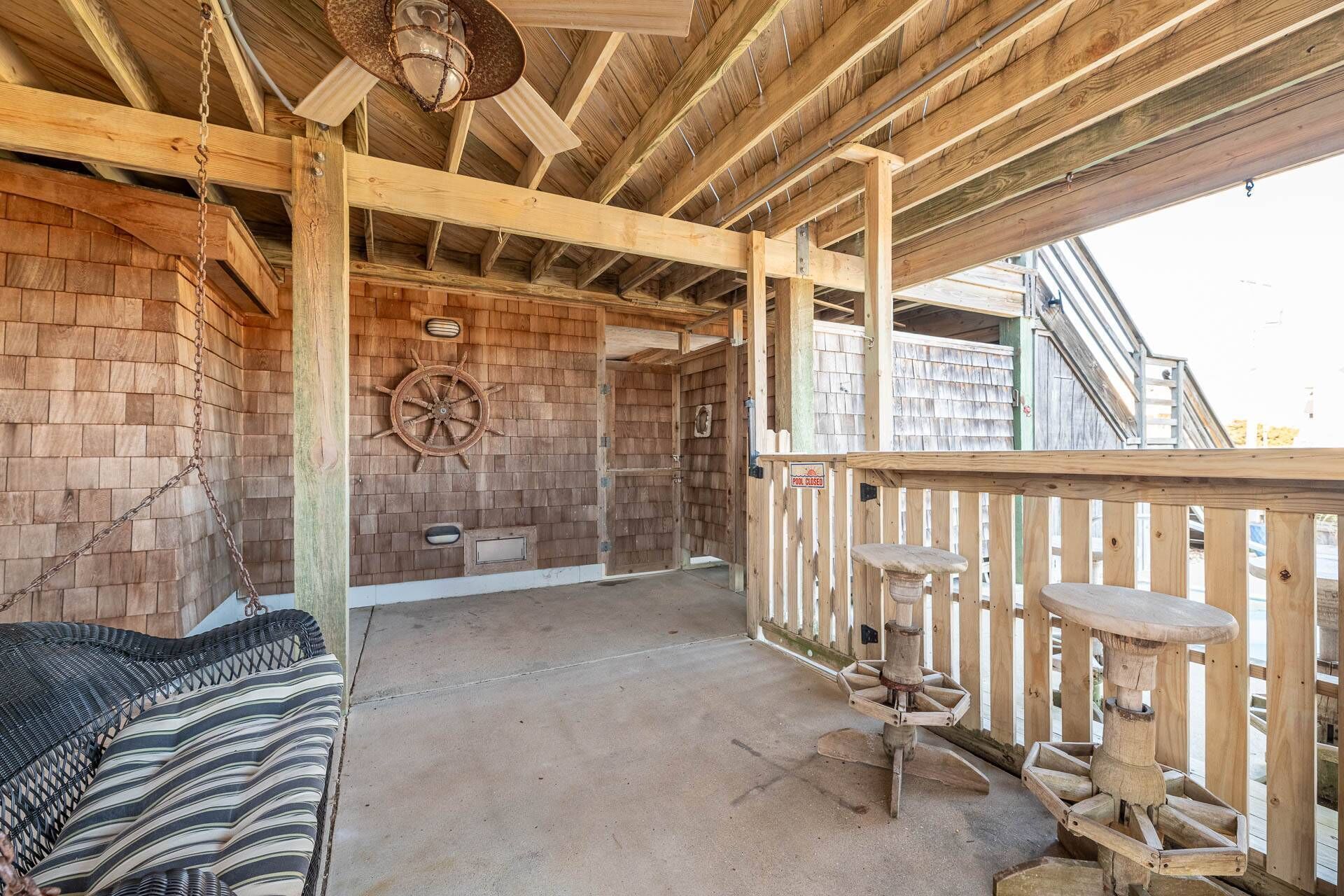 Eine Holzterrasse mit Schaukelstuhl, einer Bar aus Holz und einer Schiffslenkrad-Dekoration.