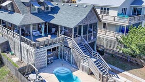 Une maison à plusieurs étages dotée d’une grande terrasse, d’une piscine et d’un patio couvert.