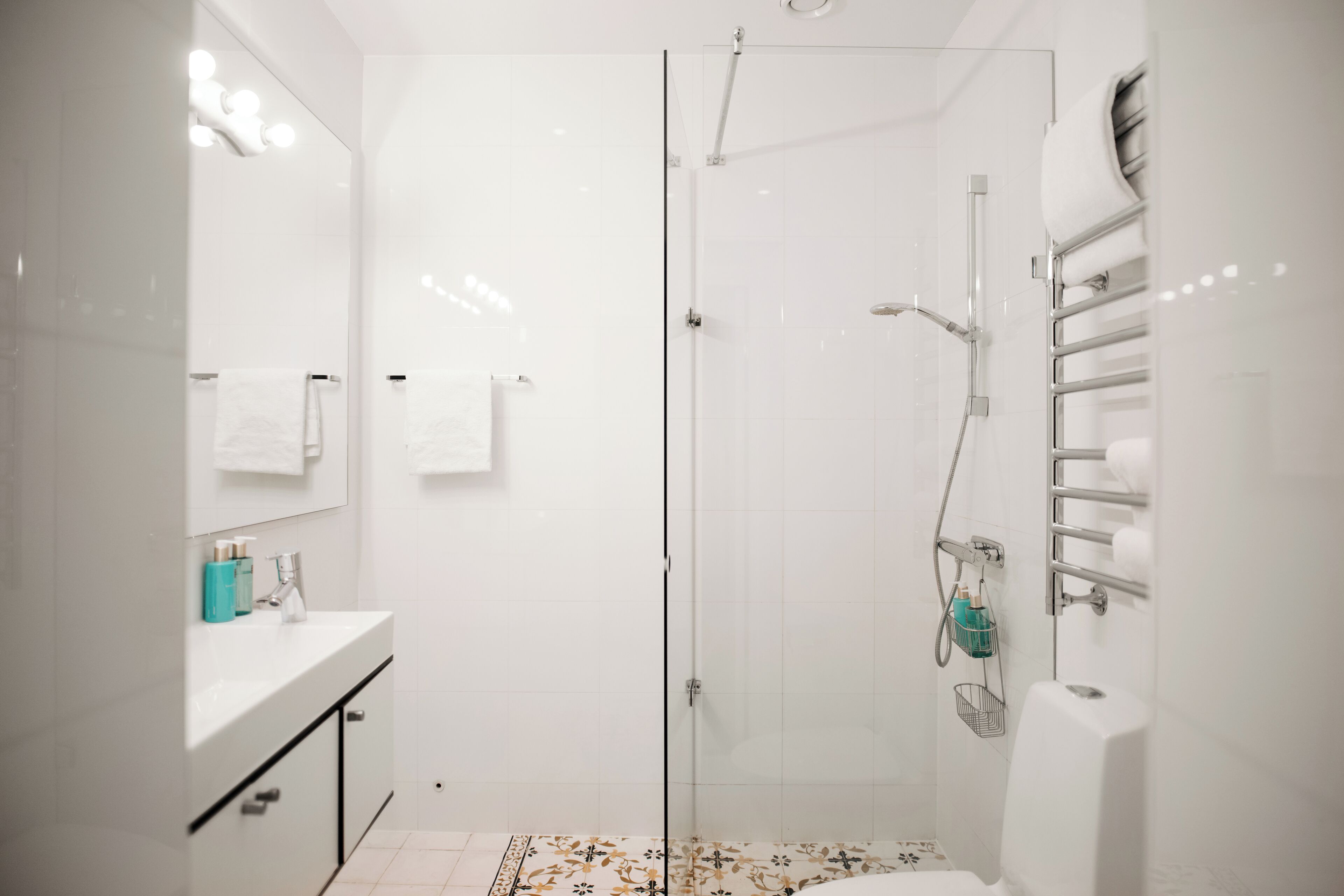 A modern bathroom with a glass shower enclosure, a white sink with a mirror, and a towel rack.
