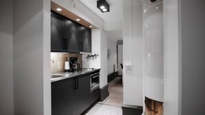 A modern kitchen with dark cabinets, a stainless steel countertop, and a built-in oven. - Guldgränd  (Stockholm)