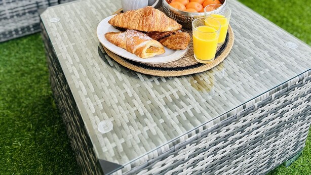 A breakfast setup on a glass table with croissants, a bowl of oranges, and glasses of orange juice. - Modern and cosy apartment with a beautiful terrace and parking, Paris La Défense (Courbevoie)