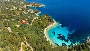 An aerial view of a coastal area with a beach, clear waters, and a marked property surrounded by greenery. - Aimilia Cottage - One Bedroom Apartment, Sleeps 2 (Longos)